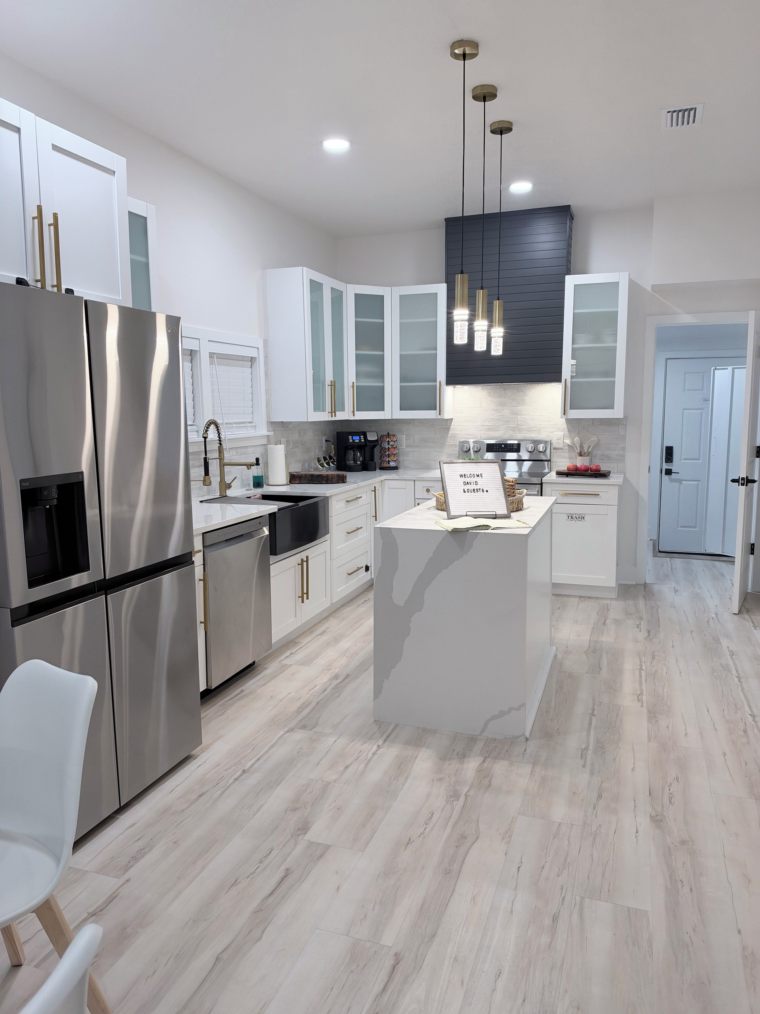 A modern kitchen with white cabinetry, stainless steel appliances, and a central island.
