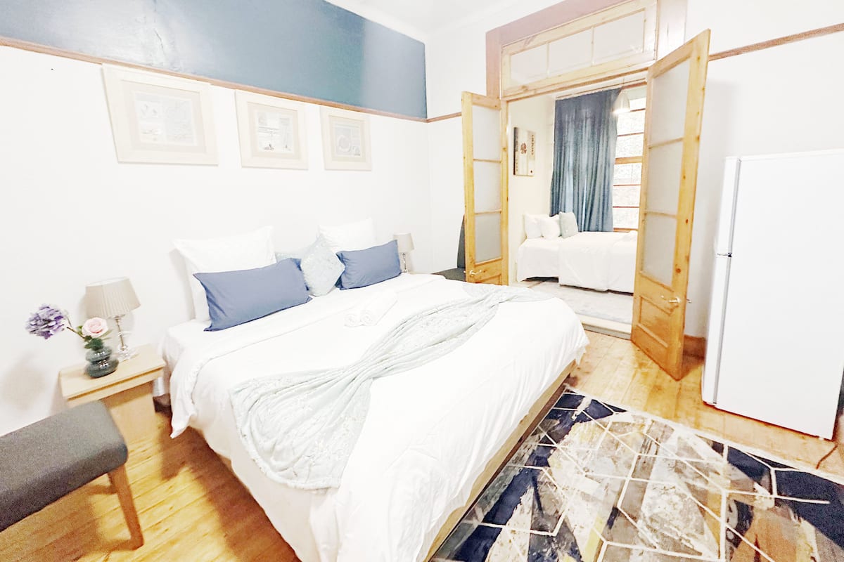 Une chambre à coucher avec un lit, une table de chevet, une lampe et une vue sur la salle de bain.