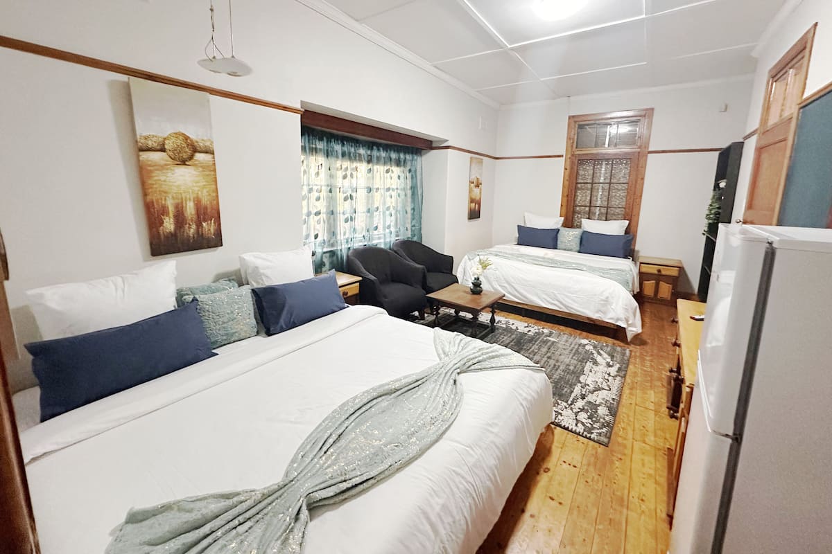 Une chambre d’hôtel avec deux lits, un bureau, une chaise, un réfrigérateur et une fenêtre avec des rideaux.