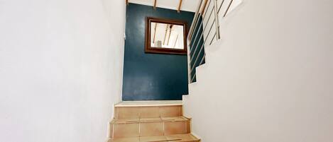 Una escalera con una pared oscura y una ventana en la parte superior.