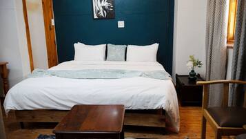 Une chambre à coucher avec un lit, une table de chevet en bois, une chaise et une petite table.