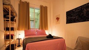 Une chambre à coucher avec un lit, une chaise, une étagère et une fenêtre avec des rideaux.