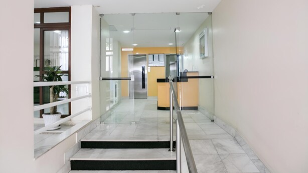 Un intérieur moderne avec un espace d ’accueil aux murs de verre, un escalier doté de rampes en métal et une plante en pot.