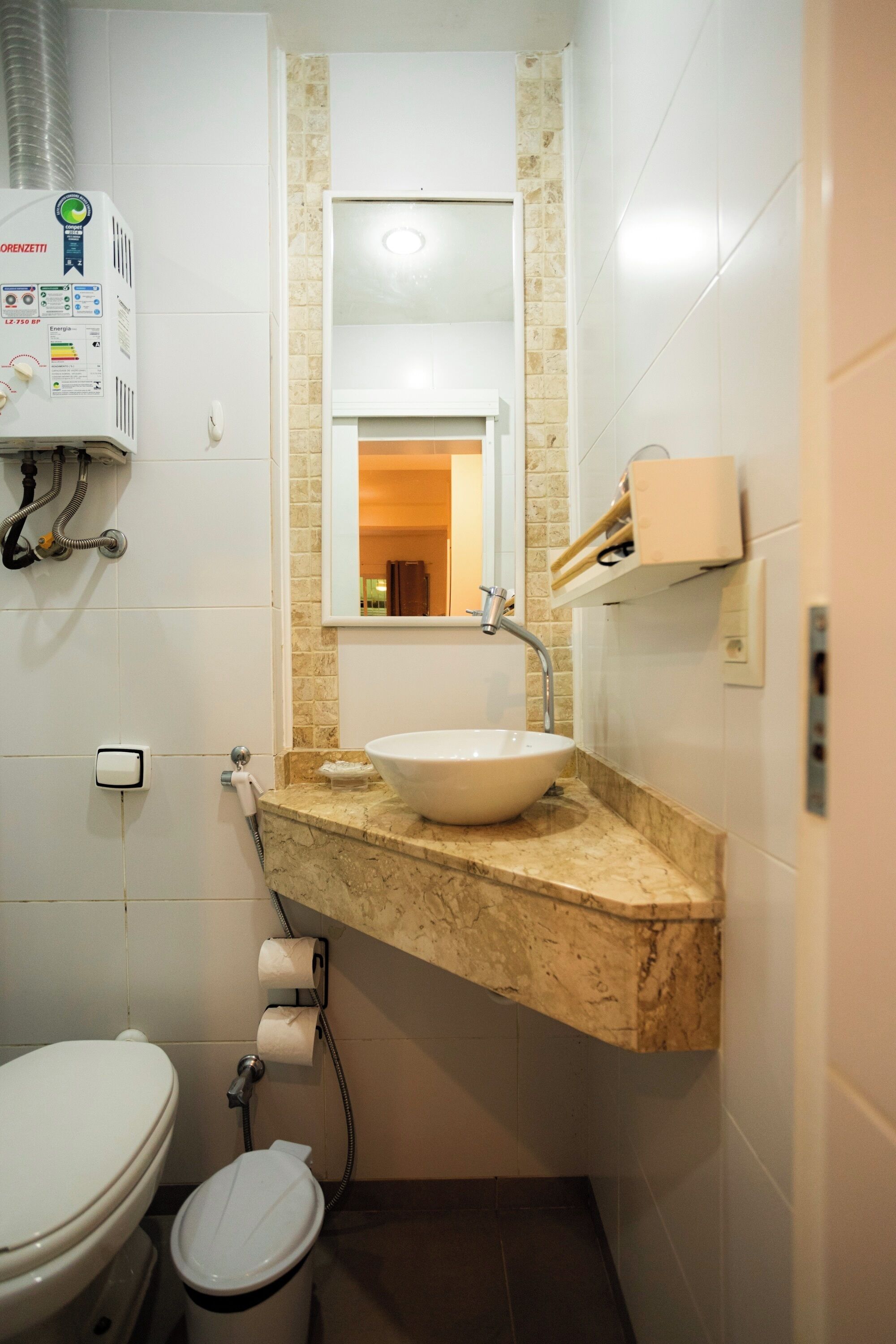A bathroom with a white toilet, a sink with a marble countertop, a mirror above the sink, and a towel rack.