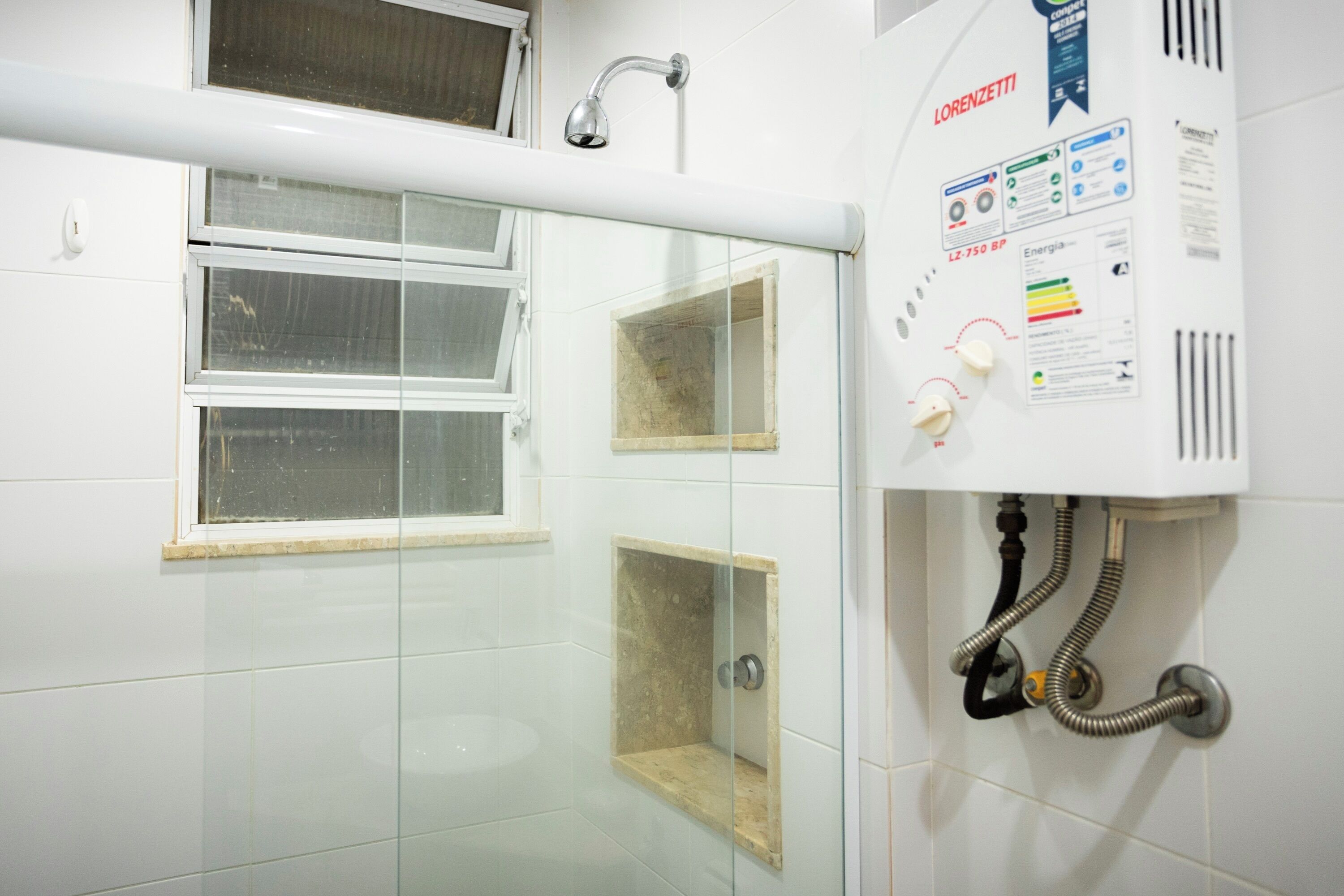A bathroom with a shower, a window, and a water heater.