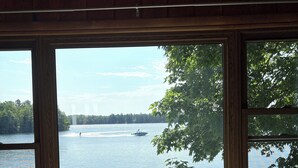 Une pièce dotée d’une grande fenêtre donnant sur un lac, une table avec un set de table et un bol décoratif.