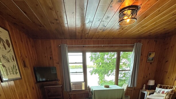 Une chambre dans un chalet en bois, équipée de deux lits, d’une télévision, d’une table et d’une chaise.