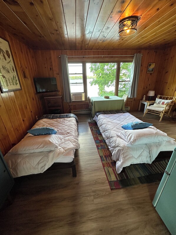 Een houten kamer met twee bedden, een televisie, een tafel en een stoel.