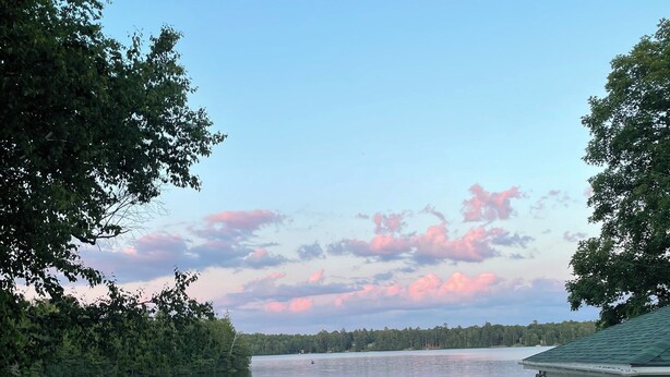 Une terrasse au bord du lac, aménagée avec du mobilier d’extérieur, un barbecue et un quai avec un bateau.