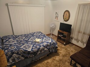A bedroom with a bed, a TV stand, a fan, and a chair. - 3-bedroom house in charming Stanton with AC, WiFi. Book now (Stanton)