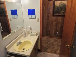 A bathroom with a sink, mirror, and a wooden door. - 3-bedroom house in charming Stanton with AC, WiFi. Book now (Stanton)