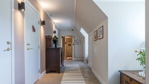 Un pasillo con suelo de madera, un tapete a rayas y un mueble de madera con detalles decorativos.
