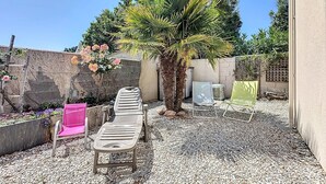 A patio area with a seating arrangement, a palm tree, and a garden with flowers.