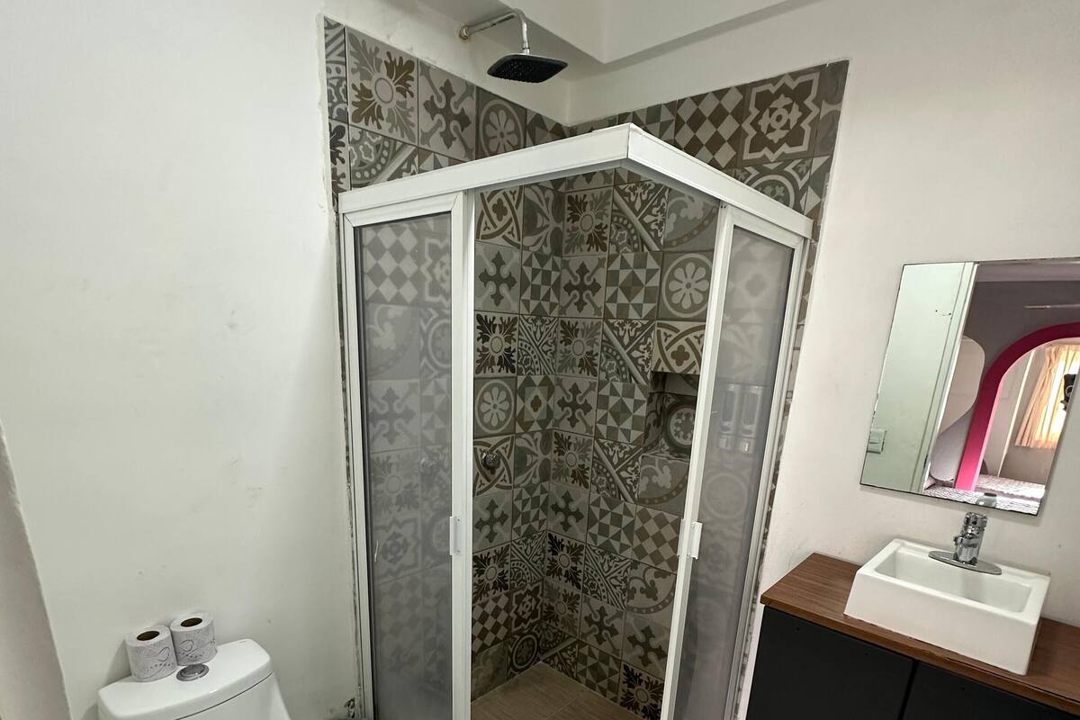 Un baño con cabina de ducha, inodoro y tocador con espejo.