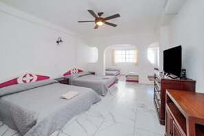 Une chambre d’hôtel avec deux lits, un ventilateur de plafond, une télévision et un bureau.