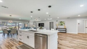 Een moderne keuken met een centraal eiland, witte kastjes en roestvrijstalen apparatuur.