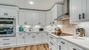 Een moderne keuken met witte kasten, een inbouwoven en een backsplash met een herringbone-patroon.