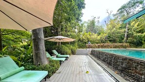 Une terrasse en bois avec des chaises longues et une piscine.