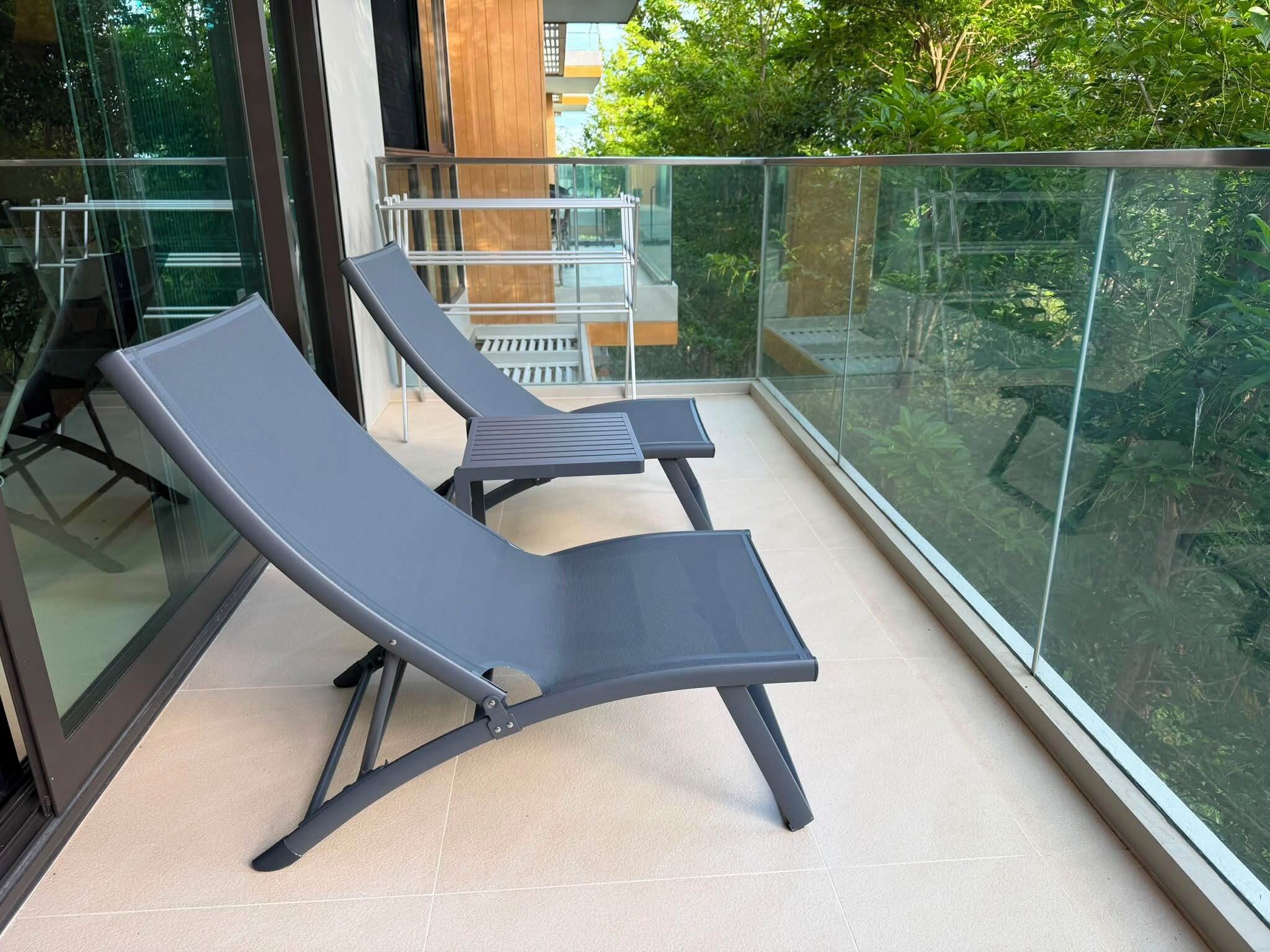 Ein Balkon mit zwei Liegestühlen und einer Glasreling.