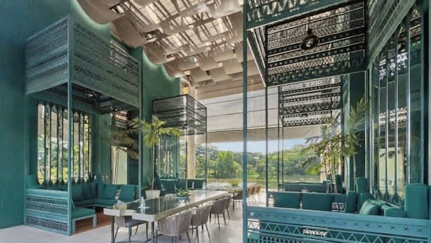 Un espace repas moderne avec une longue table, des chaises et une vue sur la verdure environnante.