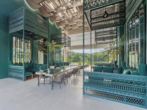 Un comedor moderno con una mesa larga, sillas y vistas al exterior con vegetación.