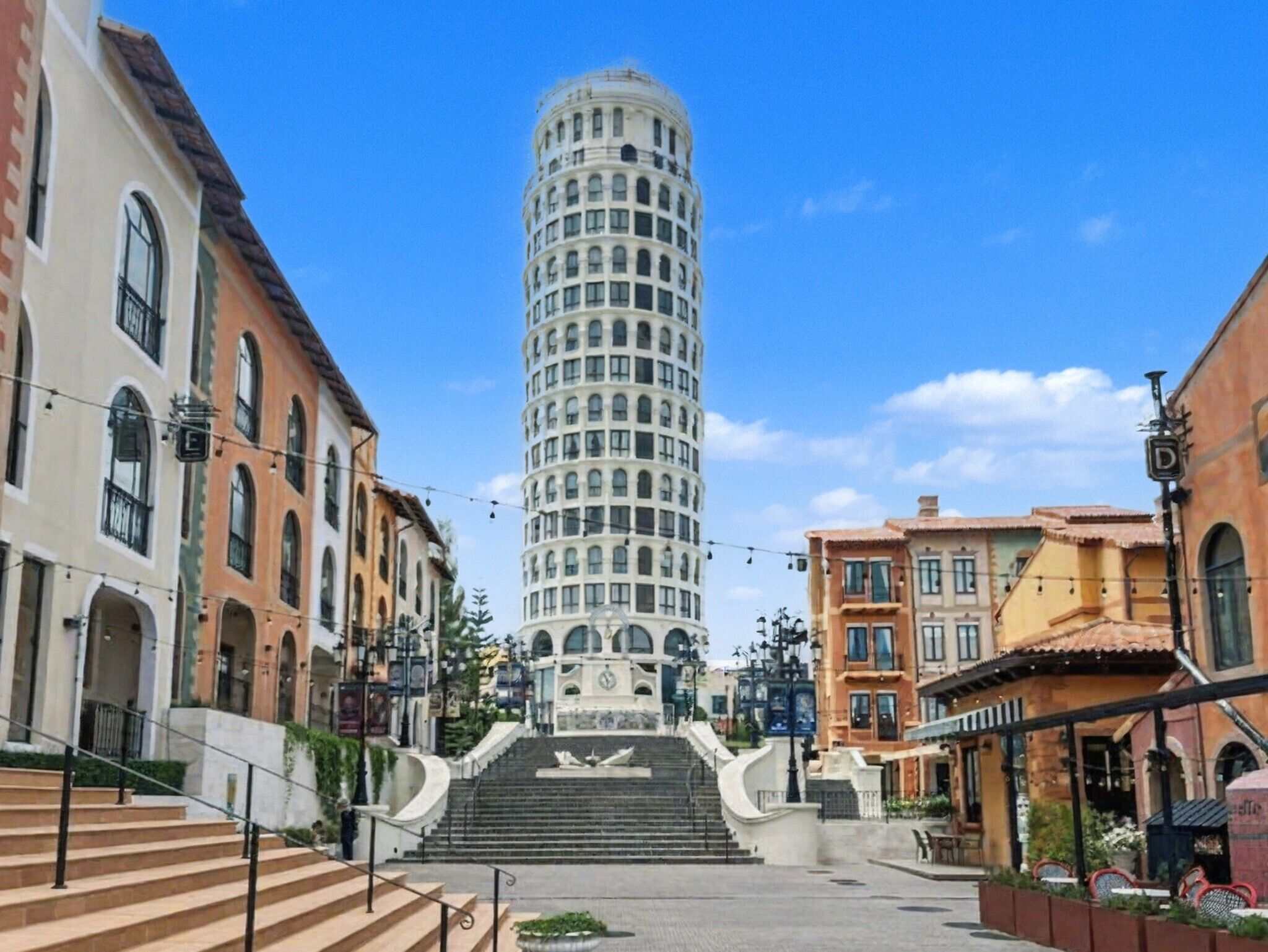 Ein historischer Turm mit einer Wendeltreppe, die zu einer zentralen Fläche führt, umgeben von traditionellen Gebäuden mit Rundbogenfenstern und Balkonen.