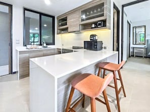 A modern kitchen with a large island, wooden cabinets, and bar stools.