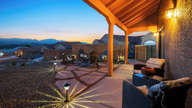 An outdoor patio with stone flooring, wooden furniture, and a view of distant mountains. - Stylish Santa Fe Escape New Home by Lake, River & Casinos! (Bullhead City)
