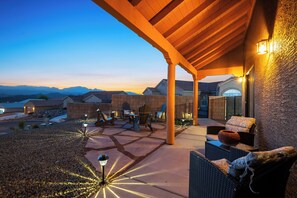 Une terrasse extérieure avec un sol en pierre, des meubles en bois et une vue sur les montagnes lointaines.
