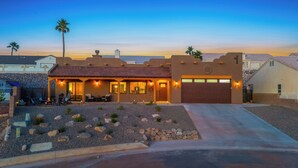 A modern house with a garage, patio with outdoor furniture, and a well-maintained garden. - Stylish Santa Fe Escape New Home by Lake, River & Casinos! (Bullhead City)