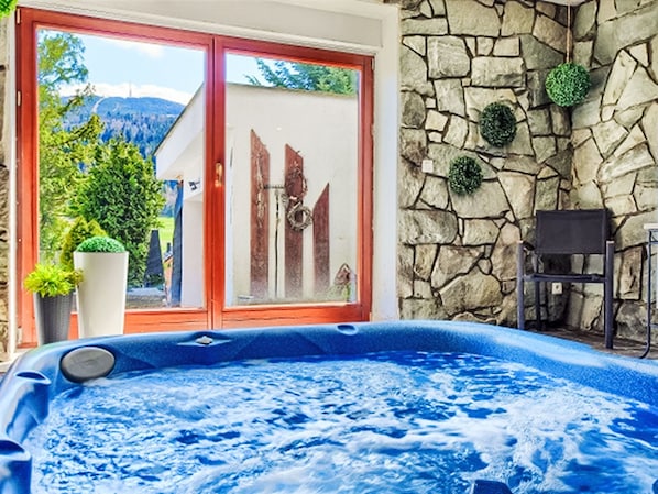 Un jacuzzi con pared de piedra y vistas a zonas verdes y montañas.