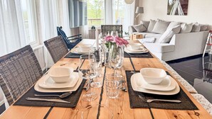 Een eetkamer met een houten tafel gedekt voor een maaltijd, omringd door rieten stoelen.