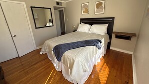Un dormitorio con una cama, un ventilador de techo, un espejo y dos cuadros en la pared.