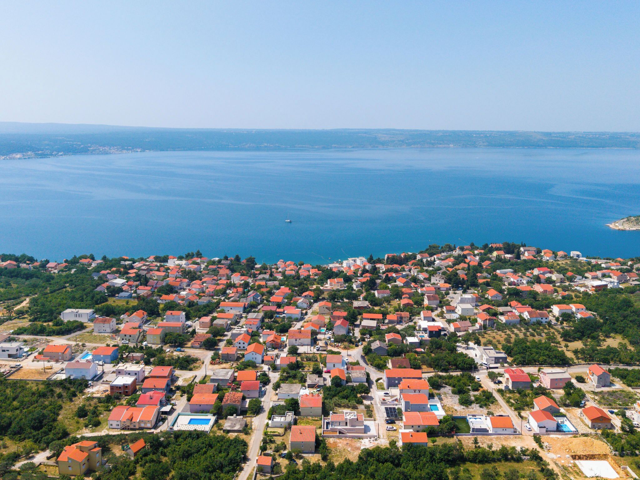 Vista aérea de uma área residencial costeira com casas, estradas e um corpo de água.