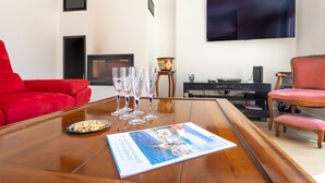 Ein modernes Wohnzimmer mit Couchtisch aus Holz, einer roten Couch und einem an der Wand befestigten Flachbildfernseher.