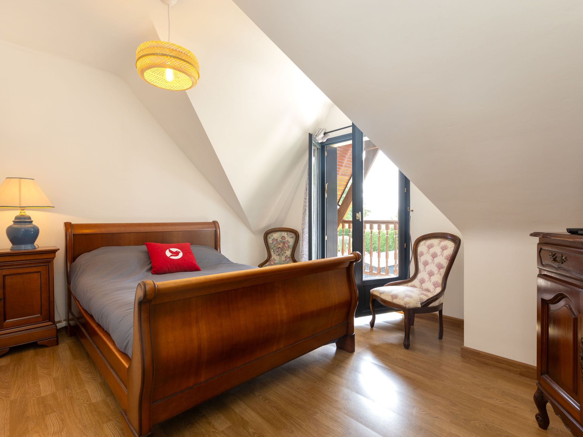 Une chambre à coucher avec un lit en bois, une table de chevet avec une lampe, une chaise et une commode.
