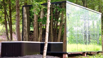 A modern, rectangular structure with a reflective glass facade, situated in a forested area.