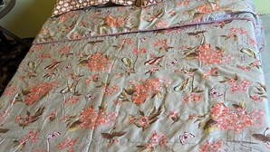 A bed with floral bedding and patterned pillows.