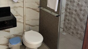 A bathroom with a toilet, a shower, a sink, and a towel rack.