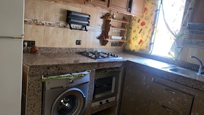 Een keuken met een wasmachine, een kookplaat en een spoelbak.