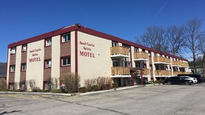 Un motel con fachada roja y color beige, varias balcones y un estacionamiento.