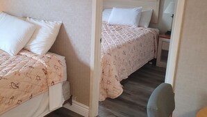 Un dormitorio con dos camas, una silla, una mesita y un espejo.