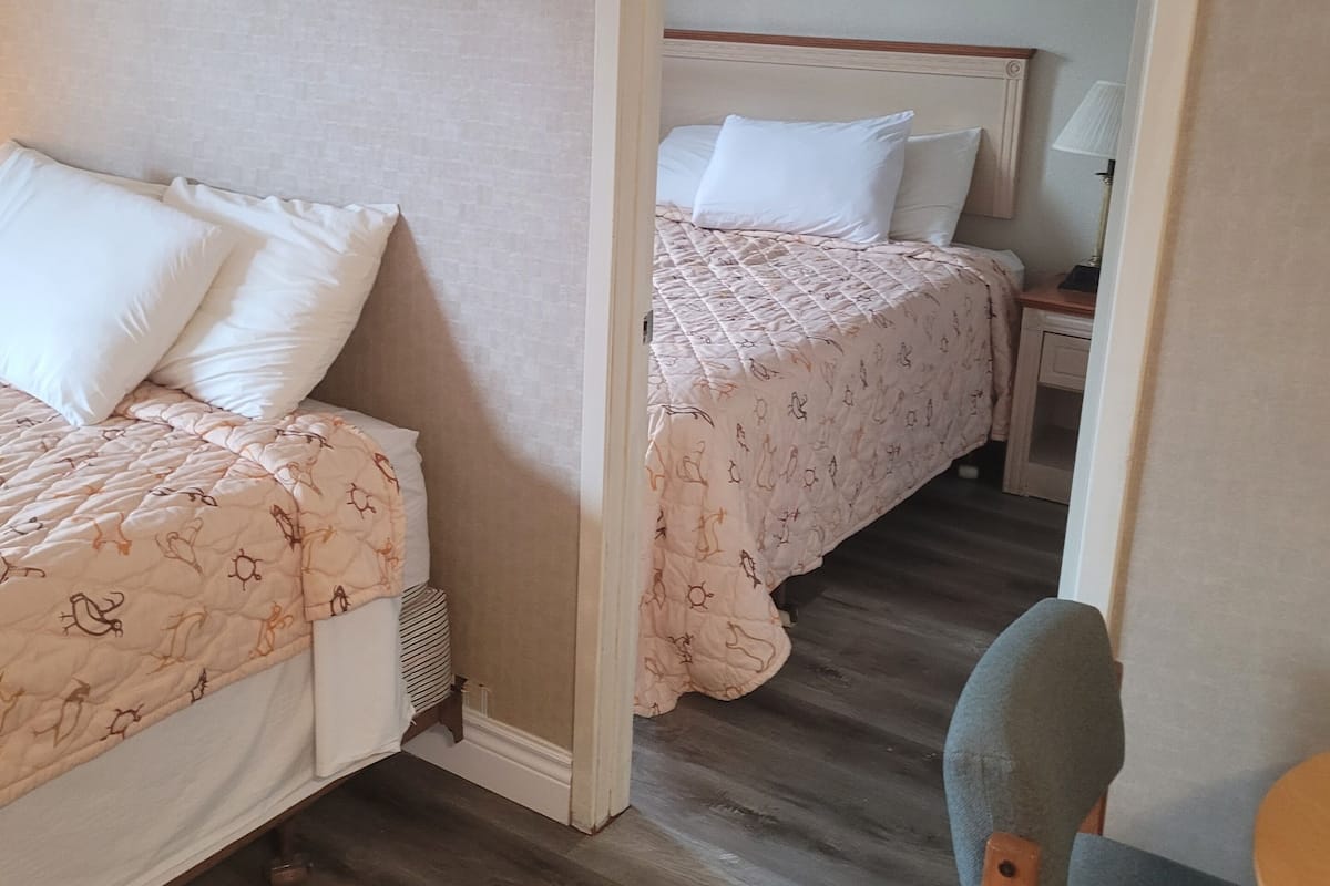 Une chambre avec deux lits, une chaise, une petite table et un miroir.