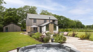 A house with a hot tub in the foreground, a patio with outdoor furniture, and a well-maintained lawn. - Highfield Barton -  Hot tub, Free Wi-Fi (Reskadinnick)