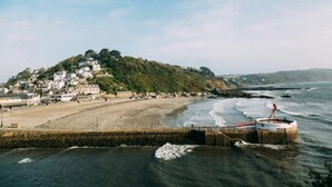 Une ville côtière dotée d’une plage, d’une jetée et de bâtiments construits sur une colline.