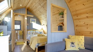 Un intérieur chaleureux, avec des éléments en bois, comprenant un lit, un canapé et un coin cuisine.