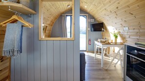Une pièce chaleureuse avec des murs et un plafond en bois, un miroir, une télévision, une table avec des chaises et un banc.