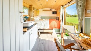 Een gezellig interieur met een bed, een bank, een tafel met ontbijt en uitzicht op de omgeving.