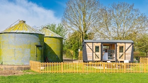 Een rustieke houten chalet met een metalen dak, omgeven door een houten hek.