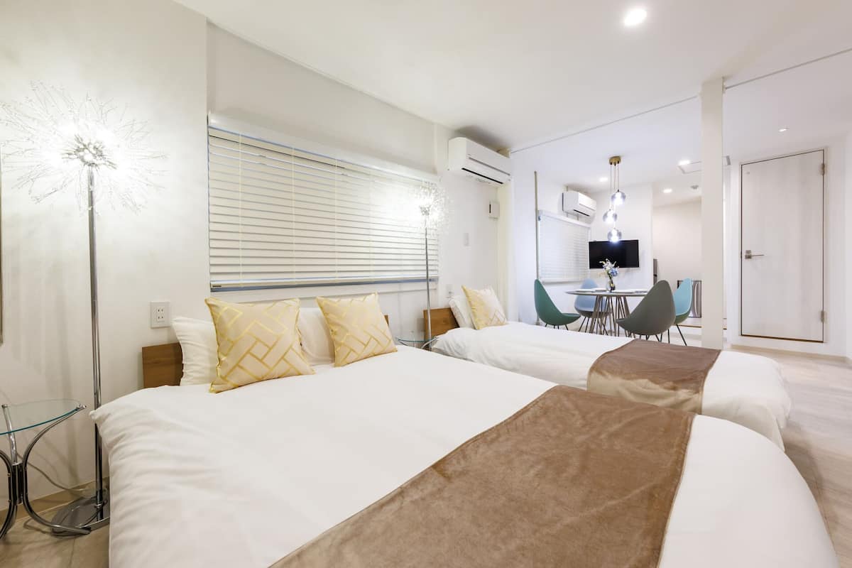 A hotel room with two beds, a desk, and a chair.